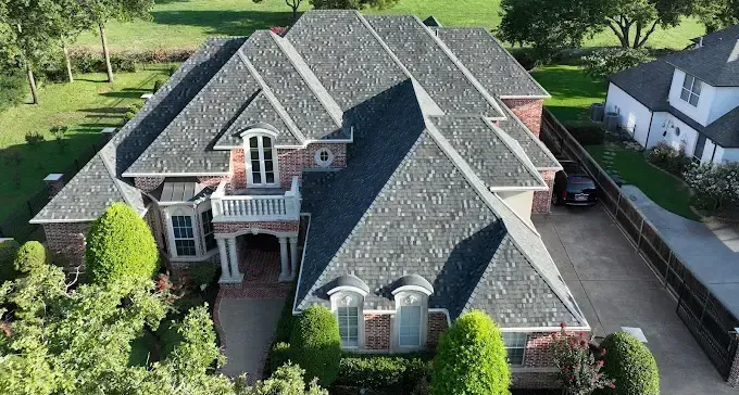 An aerial view of a house with a brown roof and a pool in the backyard.