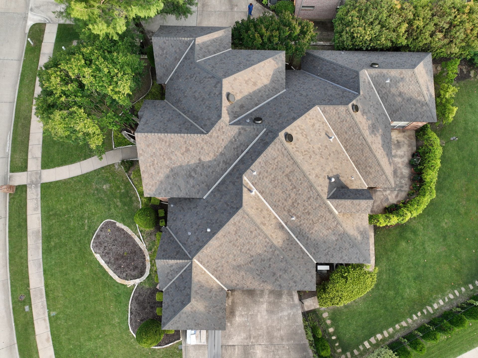 An aerial view of a house with a brown roof and a pool in the backyard.
