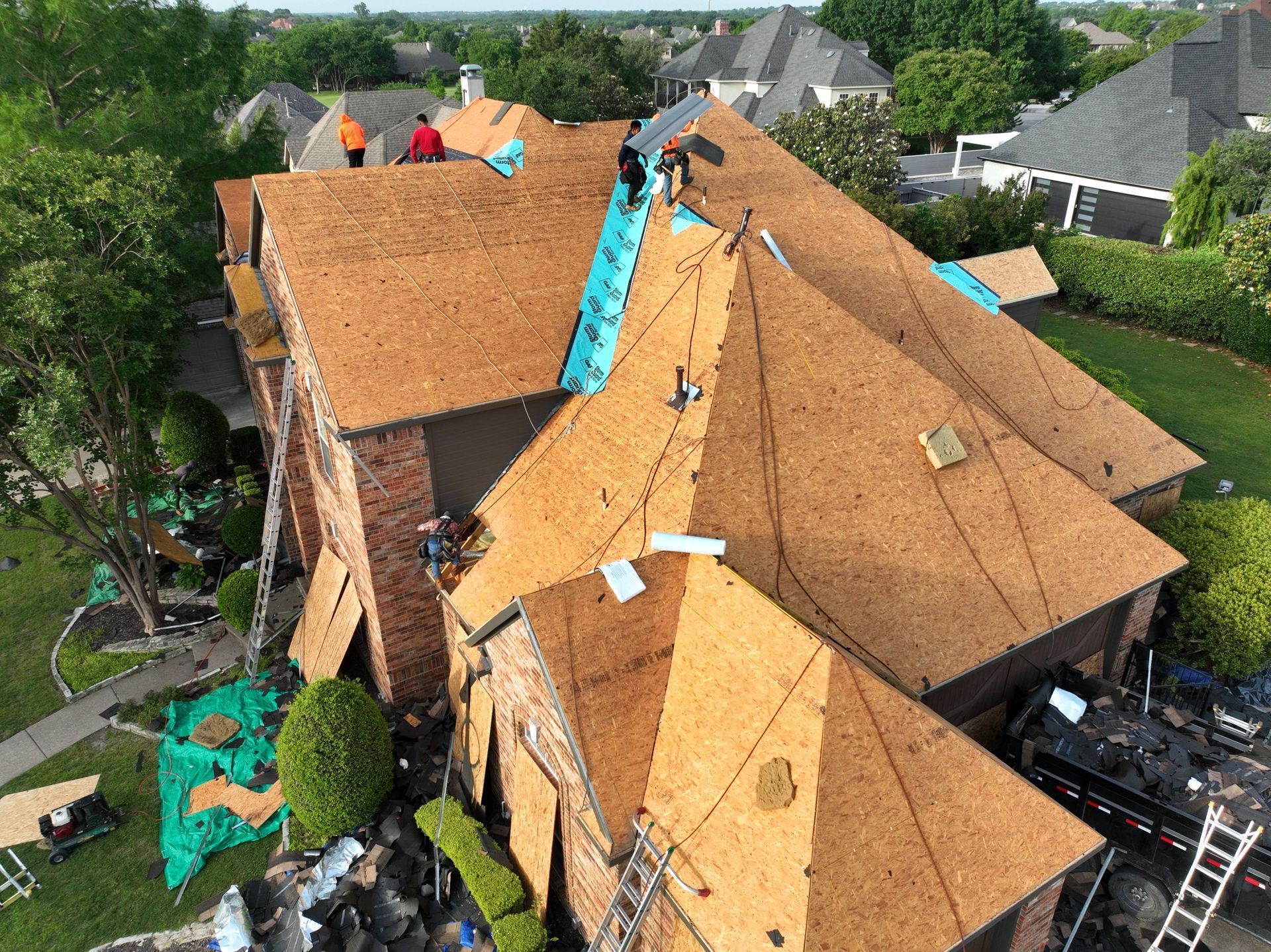 An aerial view of a house with a brown roof and a pool in the backyard.
