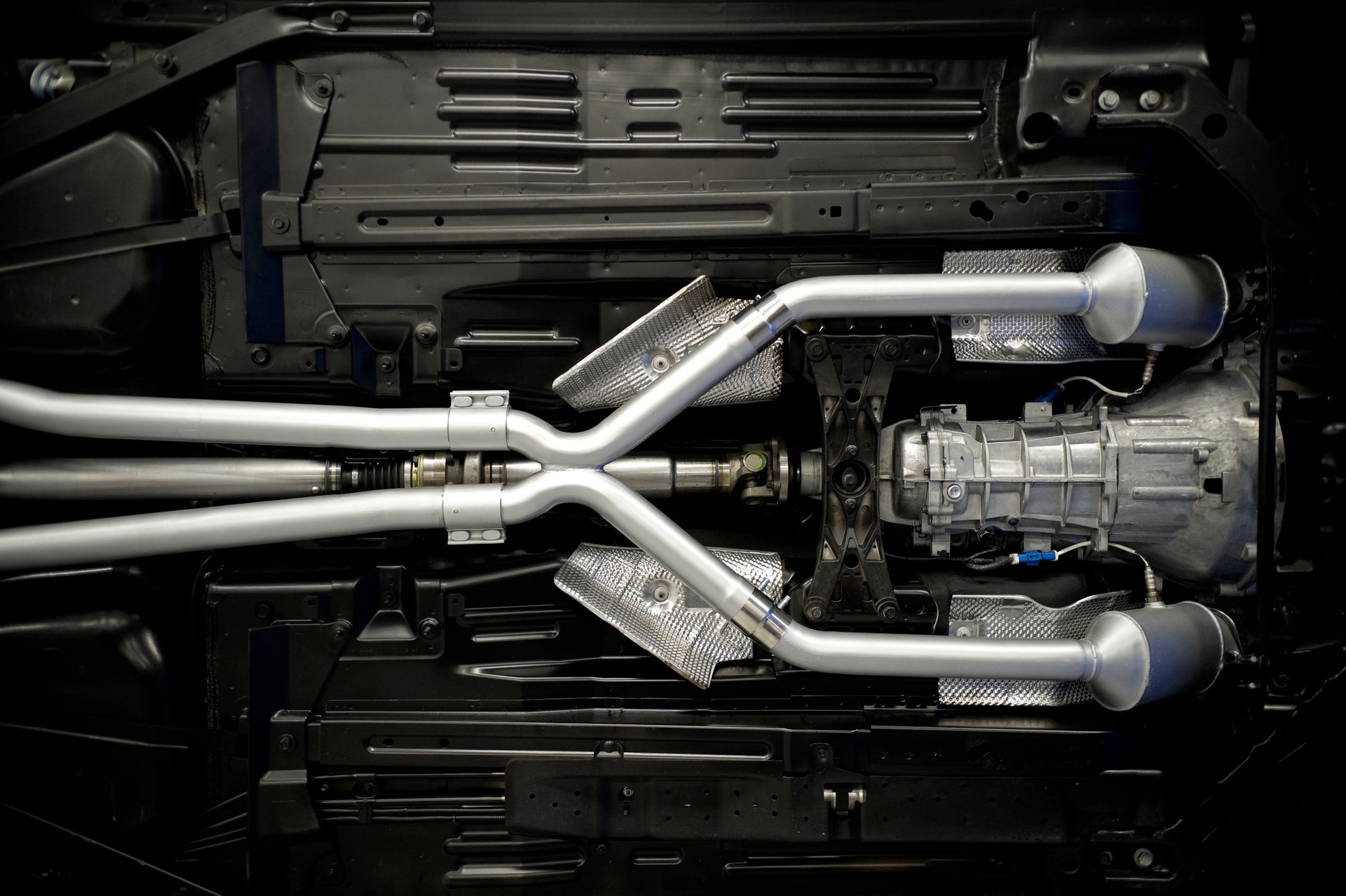 A close up of the underside of a car with exhaust pipes.