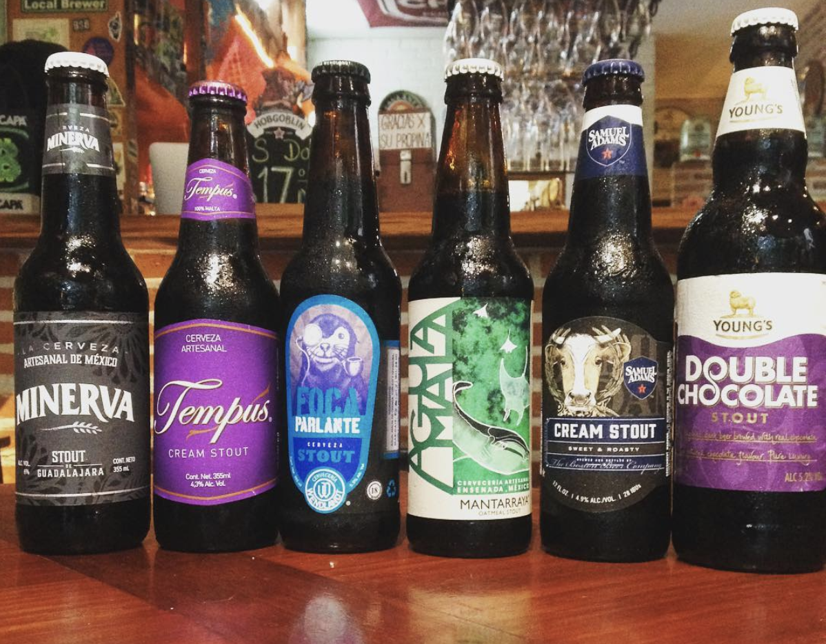 Seis botellas de cerveza en una barra, con varias etiquetas de colores.