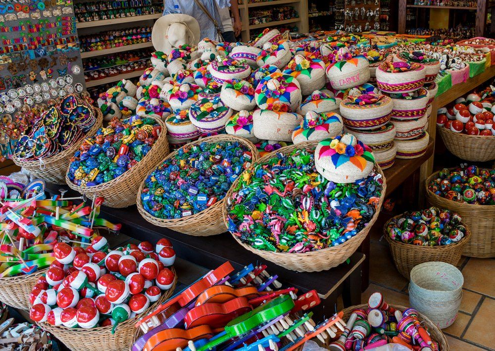 Wicker baskets overflowing with colorful Mexican crafts and ornaments at a market.