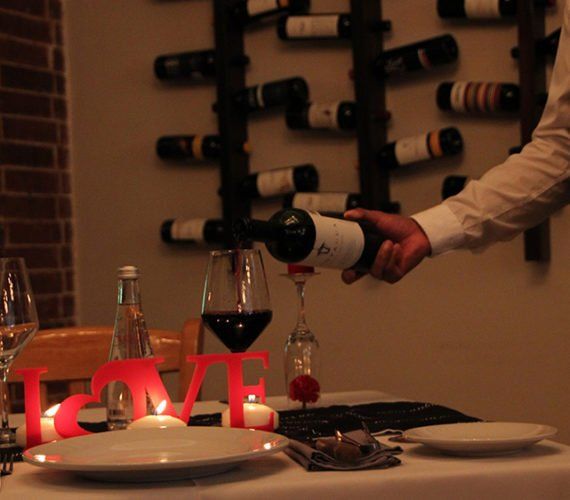 Waiter pouring red wine at a romantic table setting. 