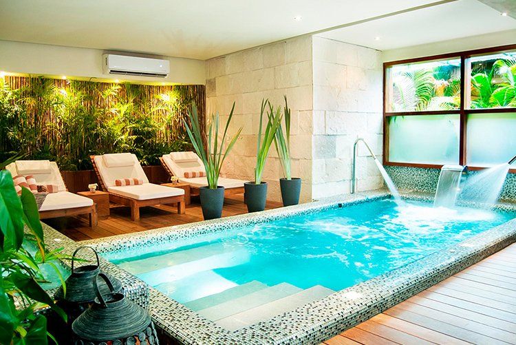 Indoor spa with a small pool, lounge chairs, bamboo, and waterfall feature.