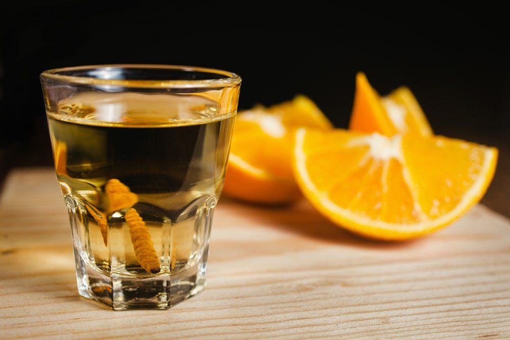 Vaso de chupito de licor con rodajas de naranja sobre una tabla de madera.
