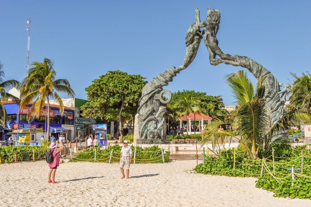 Sculpture of two figures arching towards each other on a beach in Playa del Carmen, Mexico.
