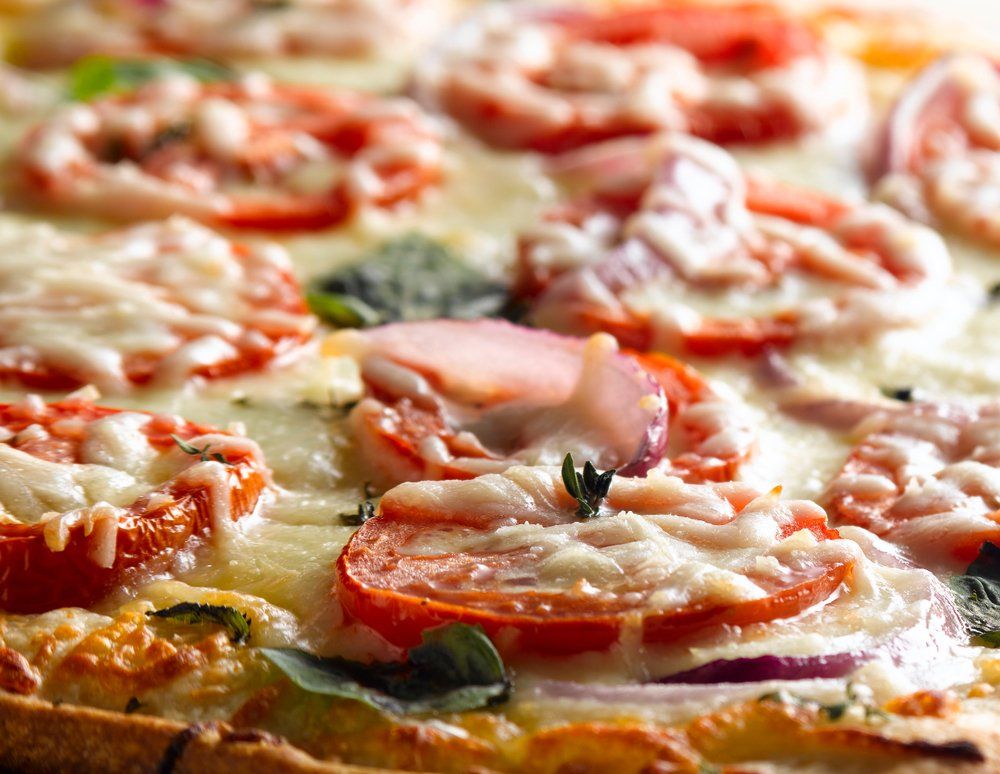 Pizza topped with sliced tomatoes, cheese, and basil.