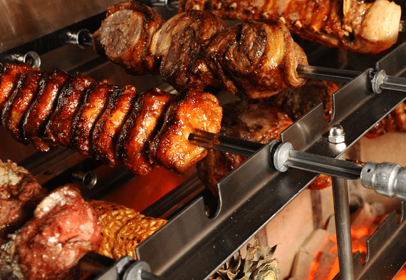 Meat on rotating skewers over a fire, cooking.