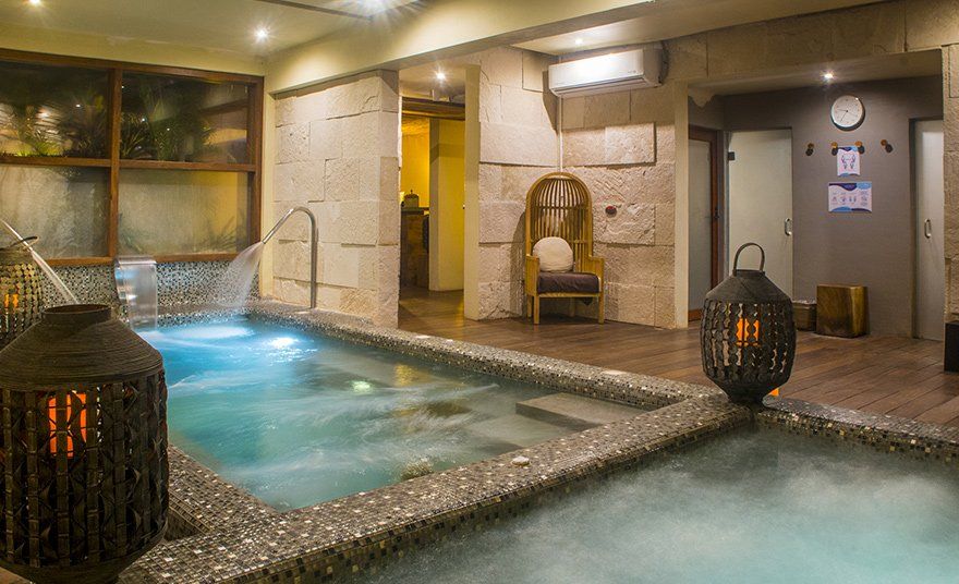 Indoor spa with stone walls, pools with water features, and lantern lighting.
