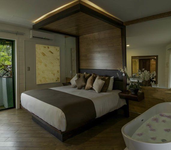 Luxurious bedroom with canopy bed, bathtub, and large mirror.