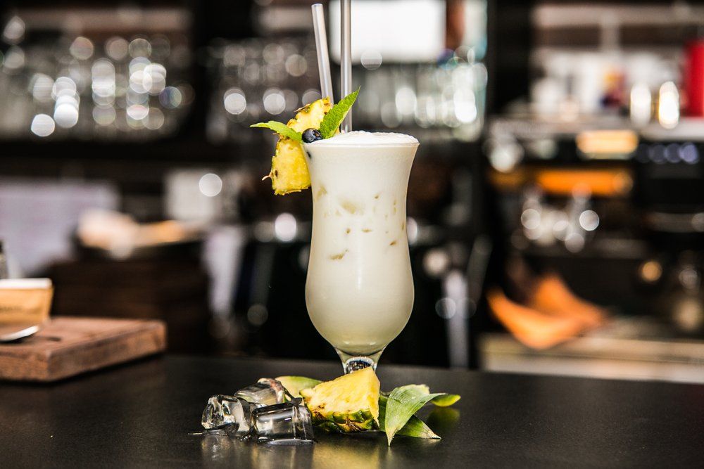 Cóctel de piña colada con guarnición de piña en una barra.