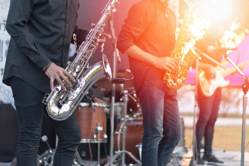 Saxophone players performing on stage with a band, lit by stage lights.