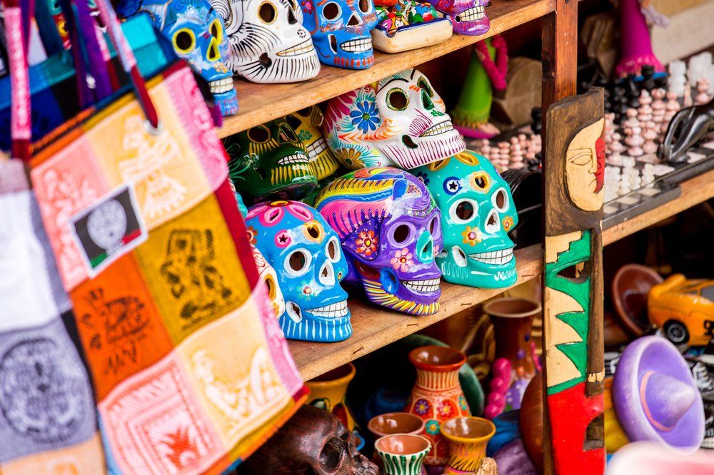 Shelves stocked with colorful ceramic sugar skulls and artisanal crafts at a market.