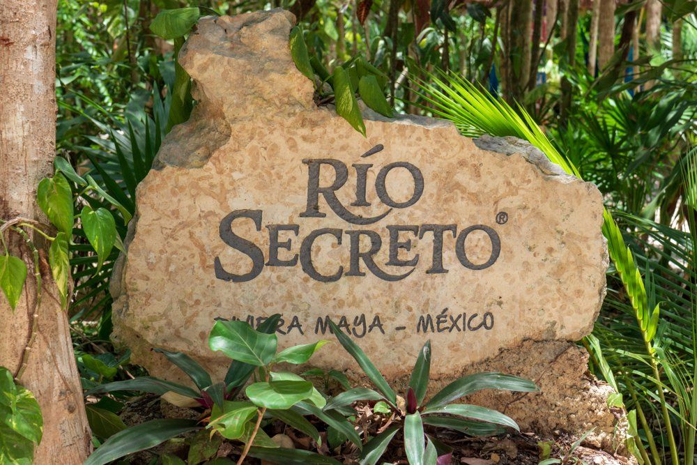 Stone sign for Río Secreto in Riviera Maya, Mexico, with text and surrounding foliage.