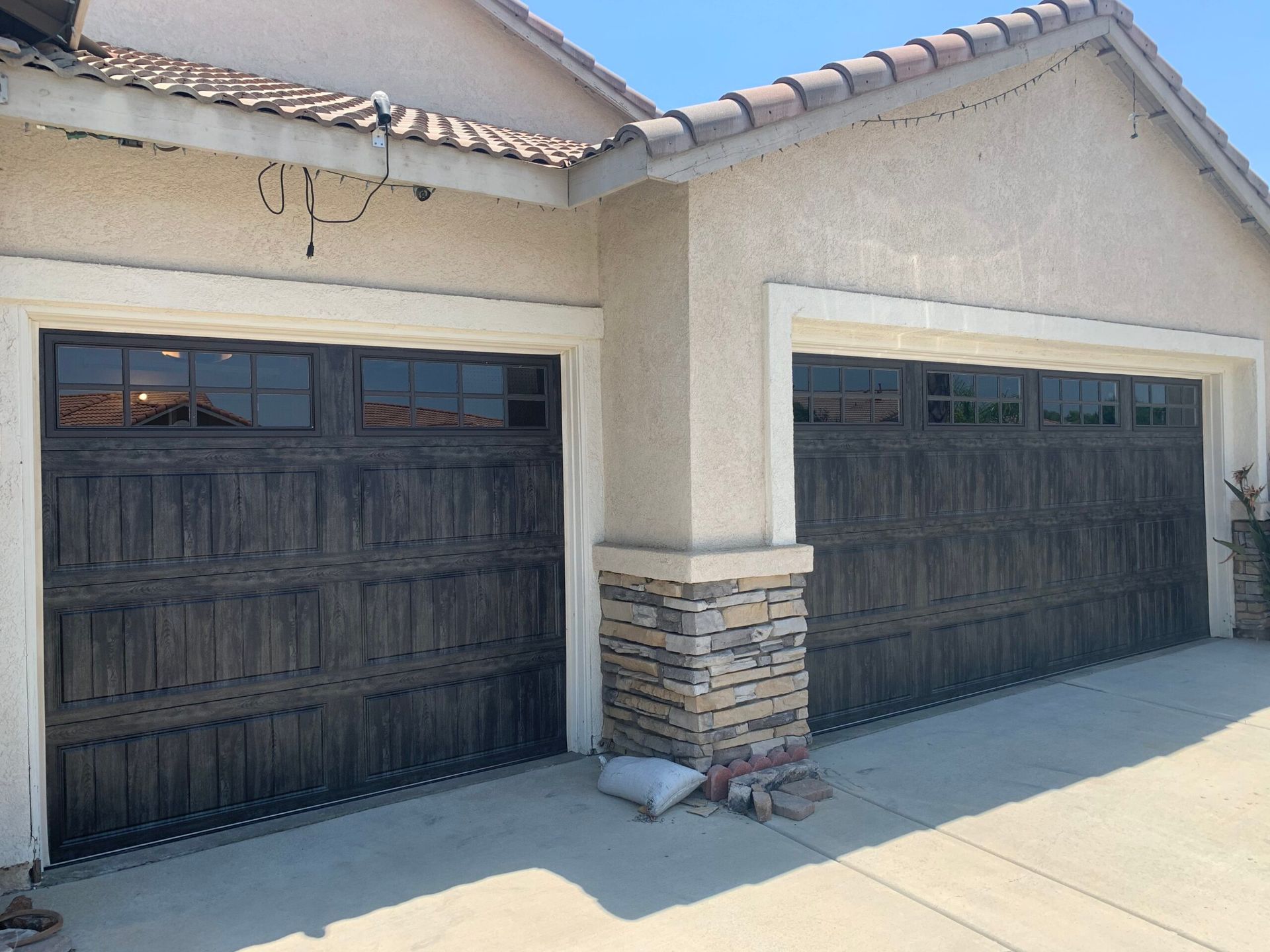 Two-car garage with dark wooden doors on a beige stucco house under a tiled roof