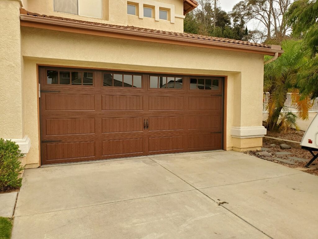 Brown two-car garage door on a beige stucco house with a concrete driveway