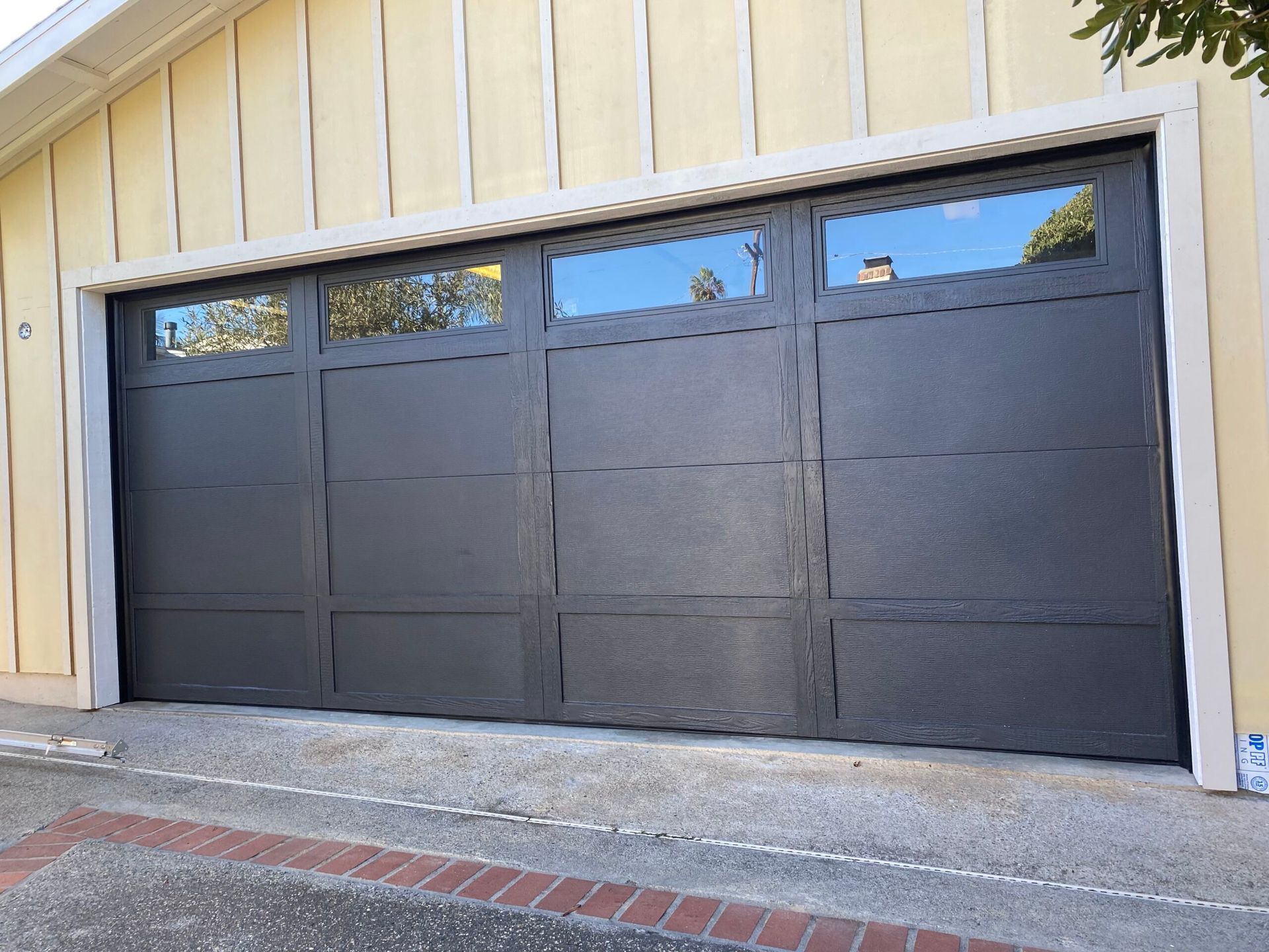 Black garage door set in a beige wall with small windows along the top.