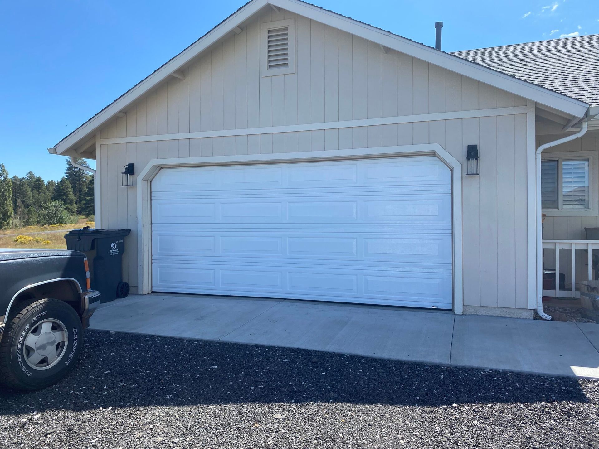 White garage door on a beige house with a black truck partly visible in the driveway.