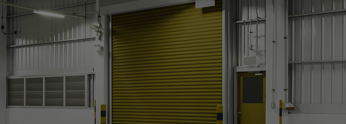 Industrial warehouse with a closed yellow roll-up door and gray metal walls