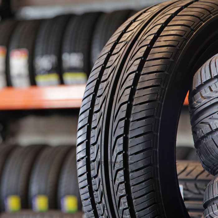 Rows of black tires stacked on shelves in a tire shop, with one tire in the foreground.