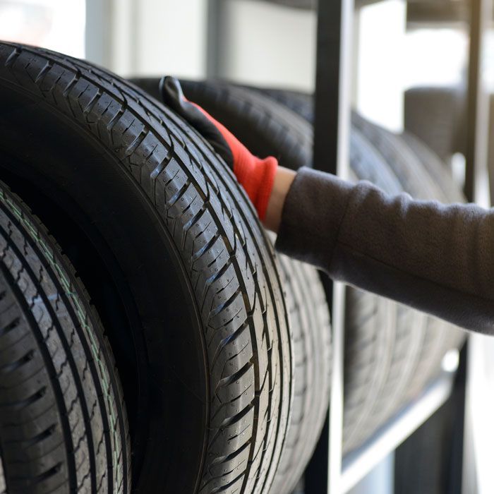 Person reaching toward stacked car tires in a warehouse