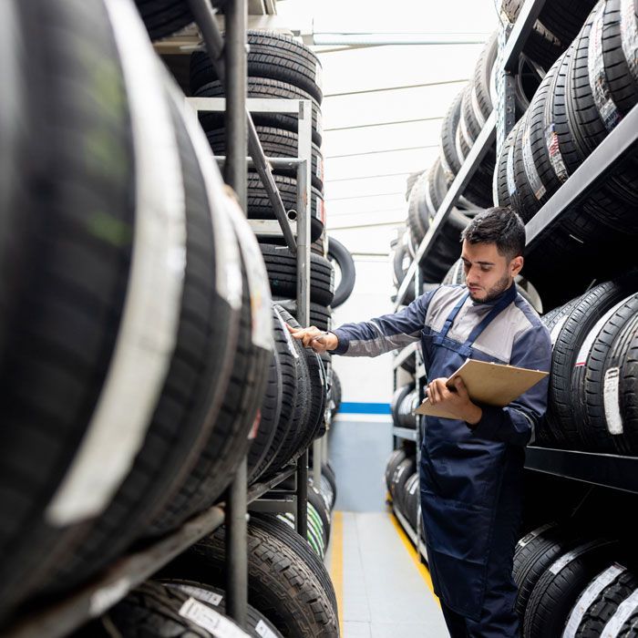 Worker with clipboard checking tires in a warehouse aisle