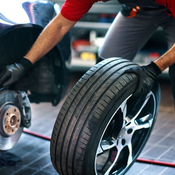 Mechanic balancing a car wheel while installing brakes in a garage