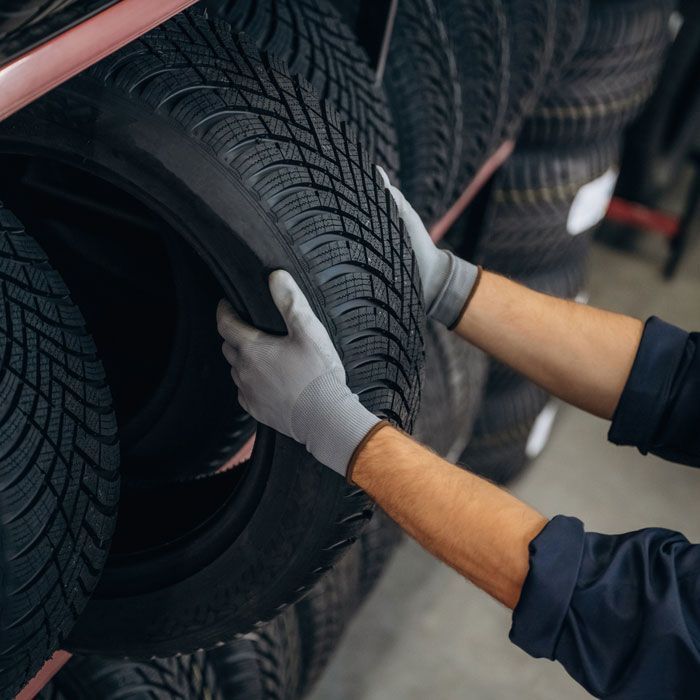 Mechanic’s gloved hands inspecting a car tire in a garage