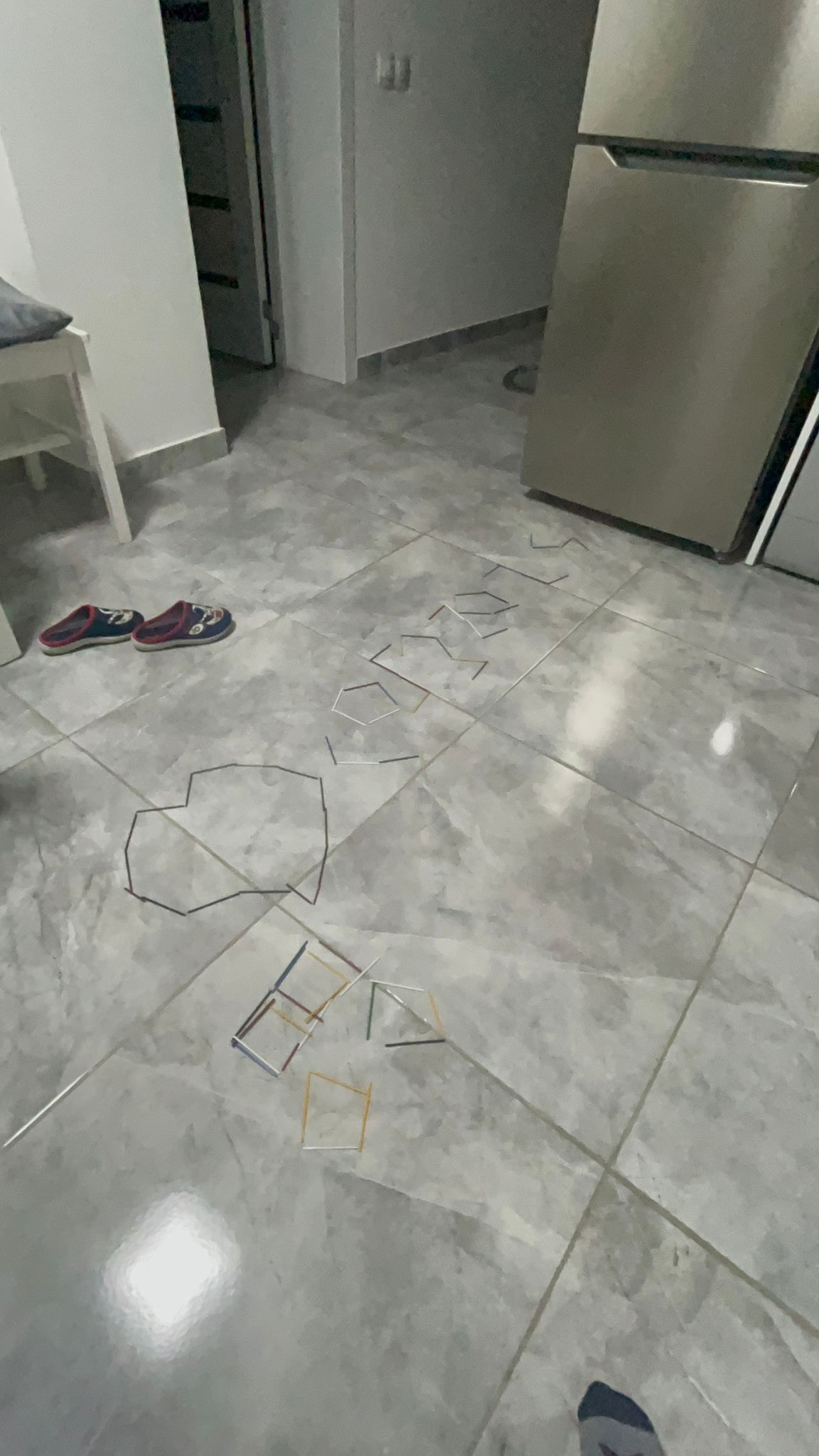 Pavimento della cucina piastrellato con frigorifero in acciaio inox e un piccolo telo per terra.