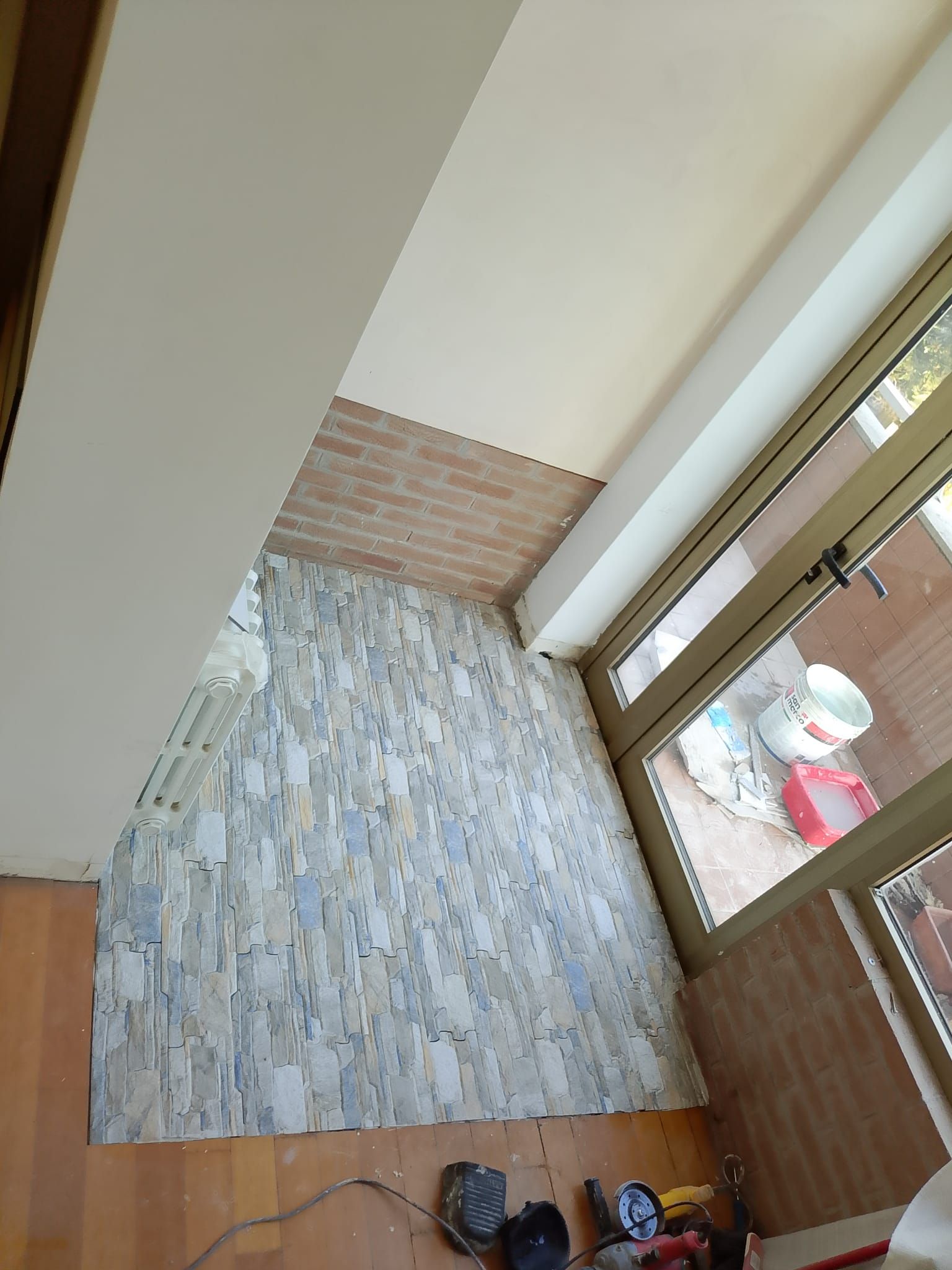 Ingresso interno vuoto con pavimento piastrellato a motivi geometrici, pannelli in legno e porta a vetri.