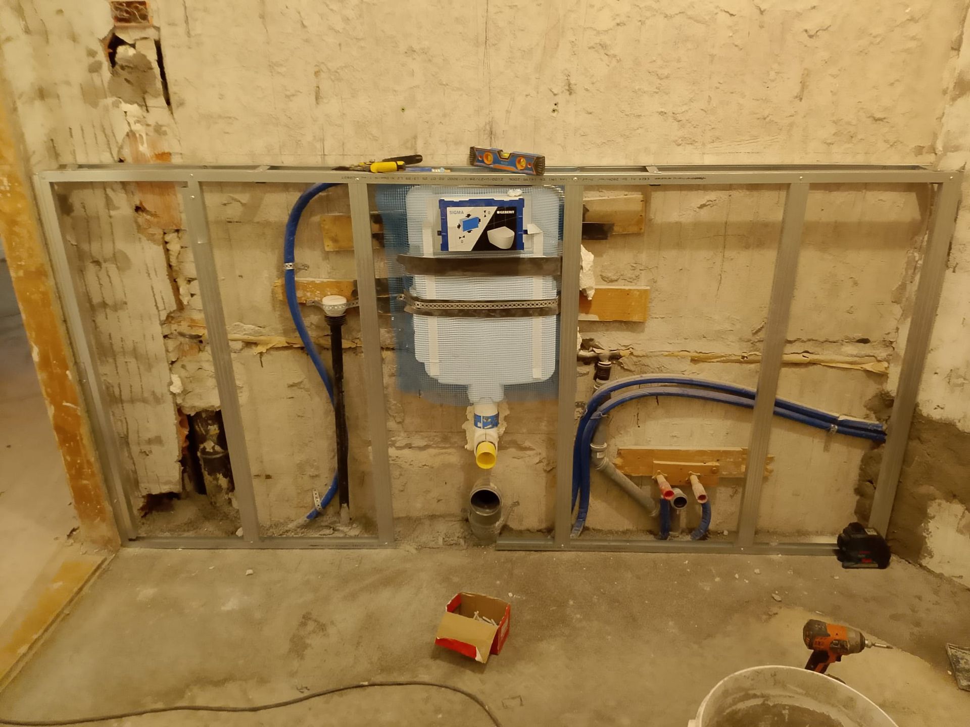 Parete con tubature a vista, contatore dell'acqua e allacciamenti alle utenze in un seminterrato non rifinito.