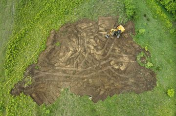 A large yellow excavator is sitting on top of a pile of dirt.