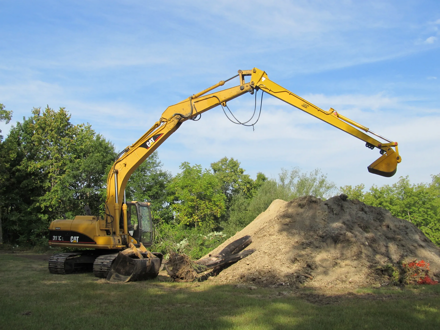 A large yellow excavator is digging in a pile of dirt