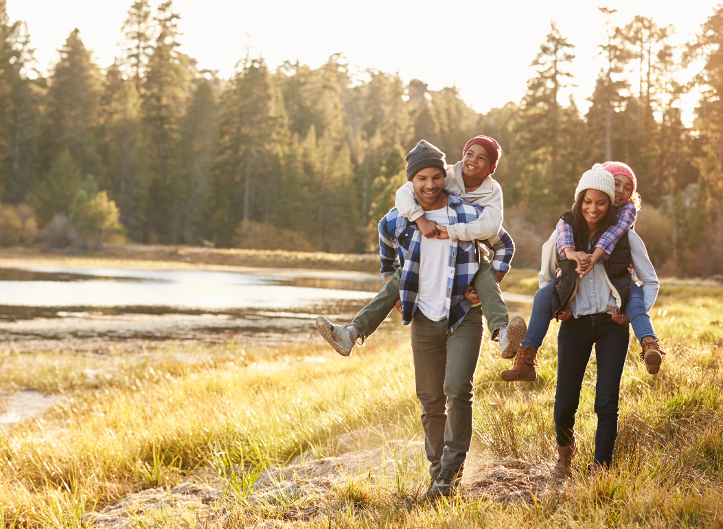 a family is walking in a field near a lake.