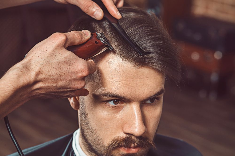 A Barber Cutting a Client's Hair With a Clipper and Comb in a Barbershop — The Gentleman's Barber QLD in Toowoomba City, QLD