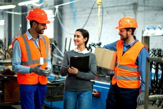 Un grupo de trabajadores de la construcción se encuentran en una fábrica hablando entre ellos.