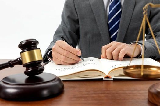 Un hombre con traje y corbata está sentado en un escritorio escribiendo en un libro.
