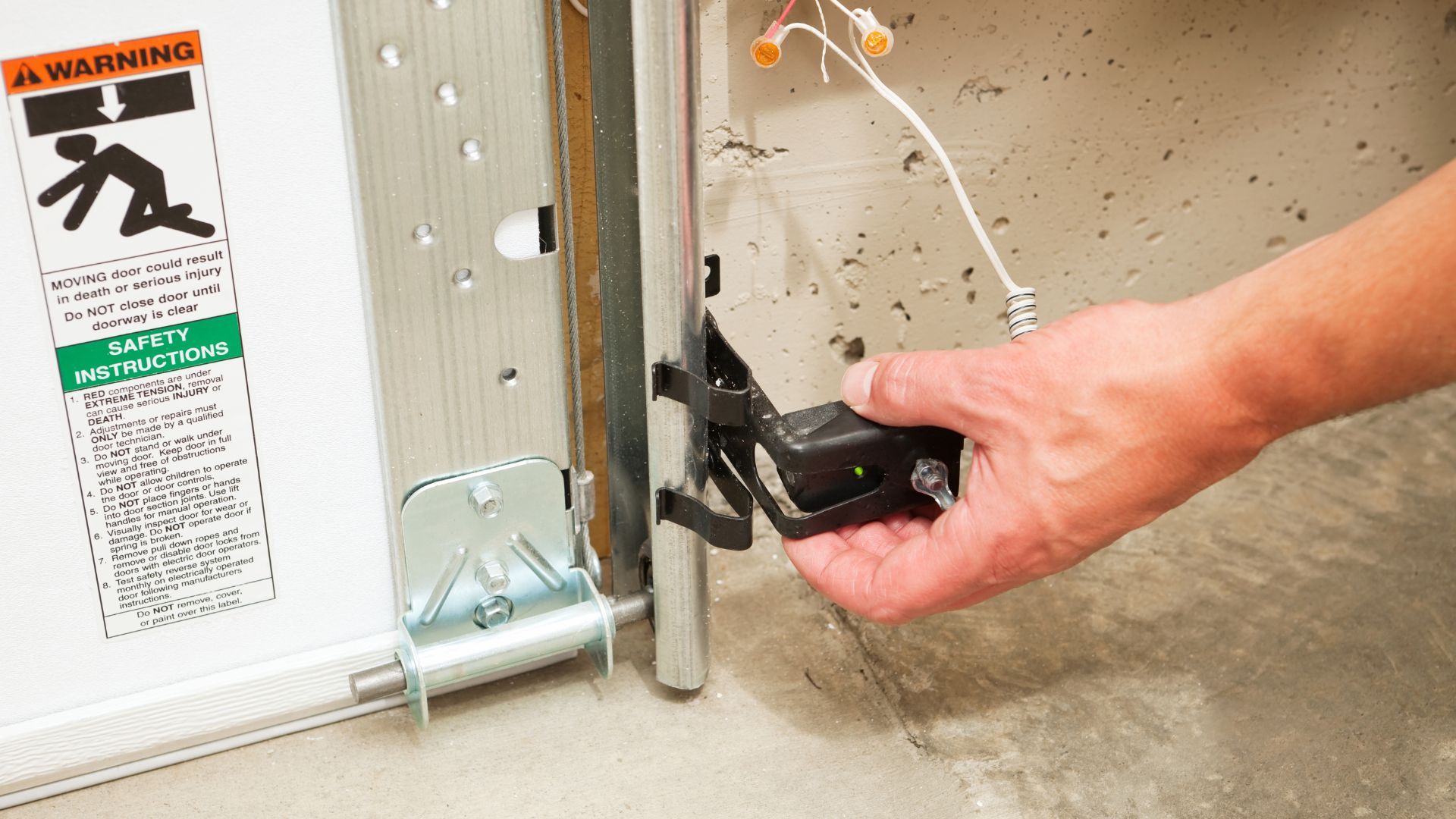 A person is fixing a garage door with a tool.