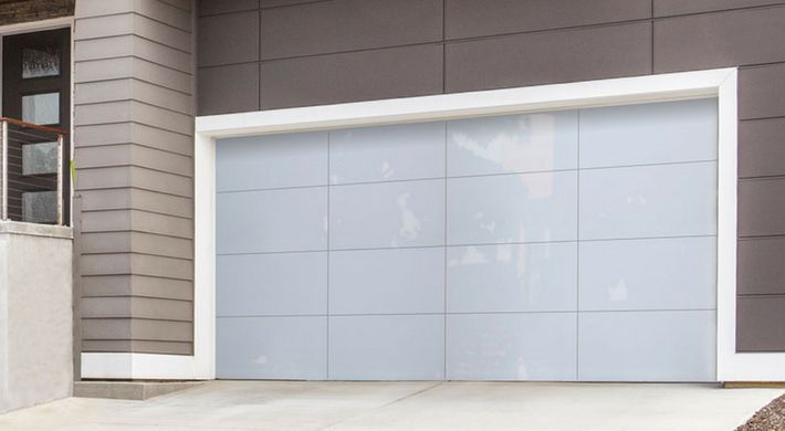 A white garage door is sitting in front of a house.
