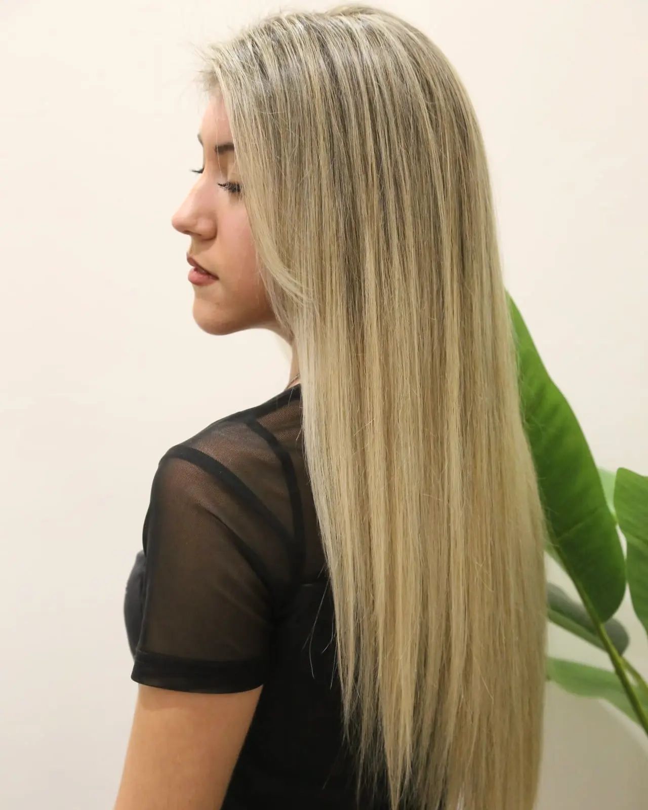 Vista di profilo di una persona con lunghi capelli biondi e lisci che indossa una maglietta nera