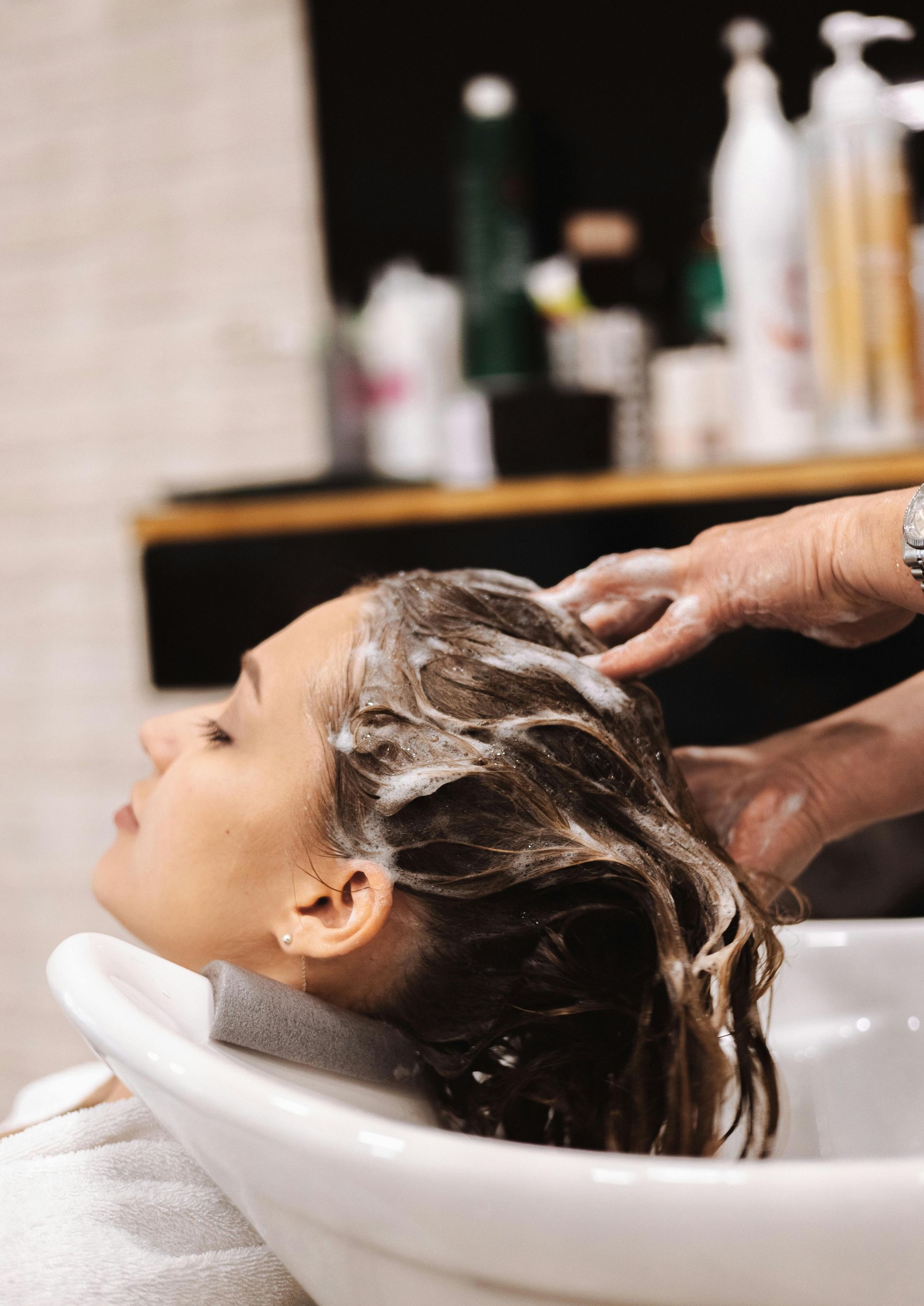 Una donna si fa lavare i capelli al lavandino di un salone di bellezza.