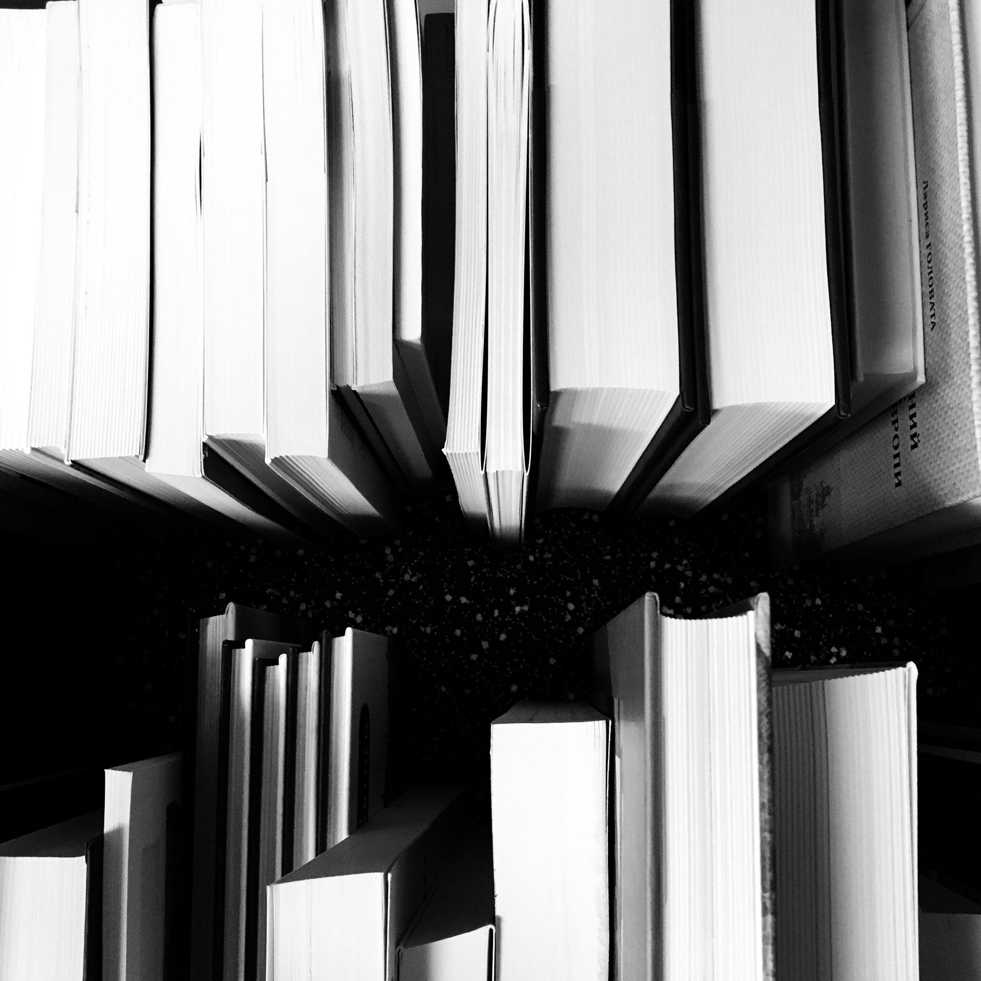 Monochrome shot of many books, close together. Upward angle, white pages, black backdrop.