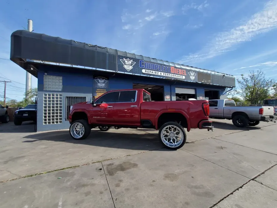 Red pickup truck parked outside a tire shop on a sunny day