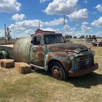 Old rusty truck with giant round hay bale