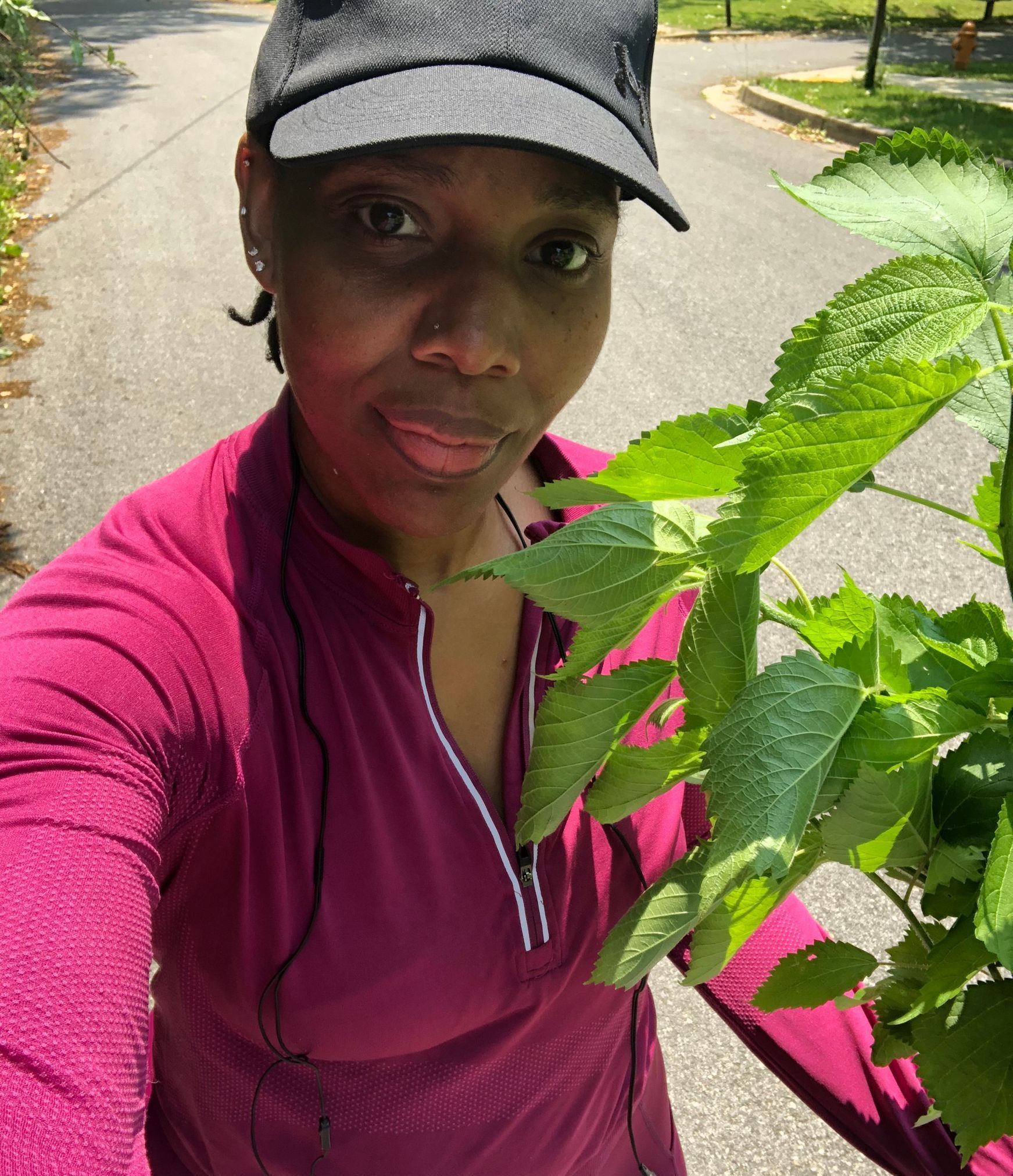A woman wearing a hat is holding a plant in her hand