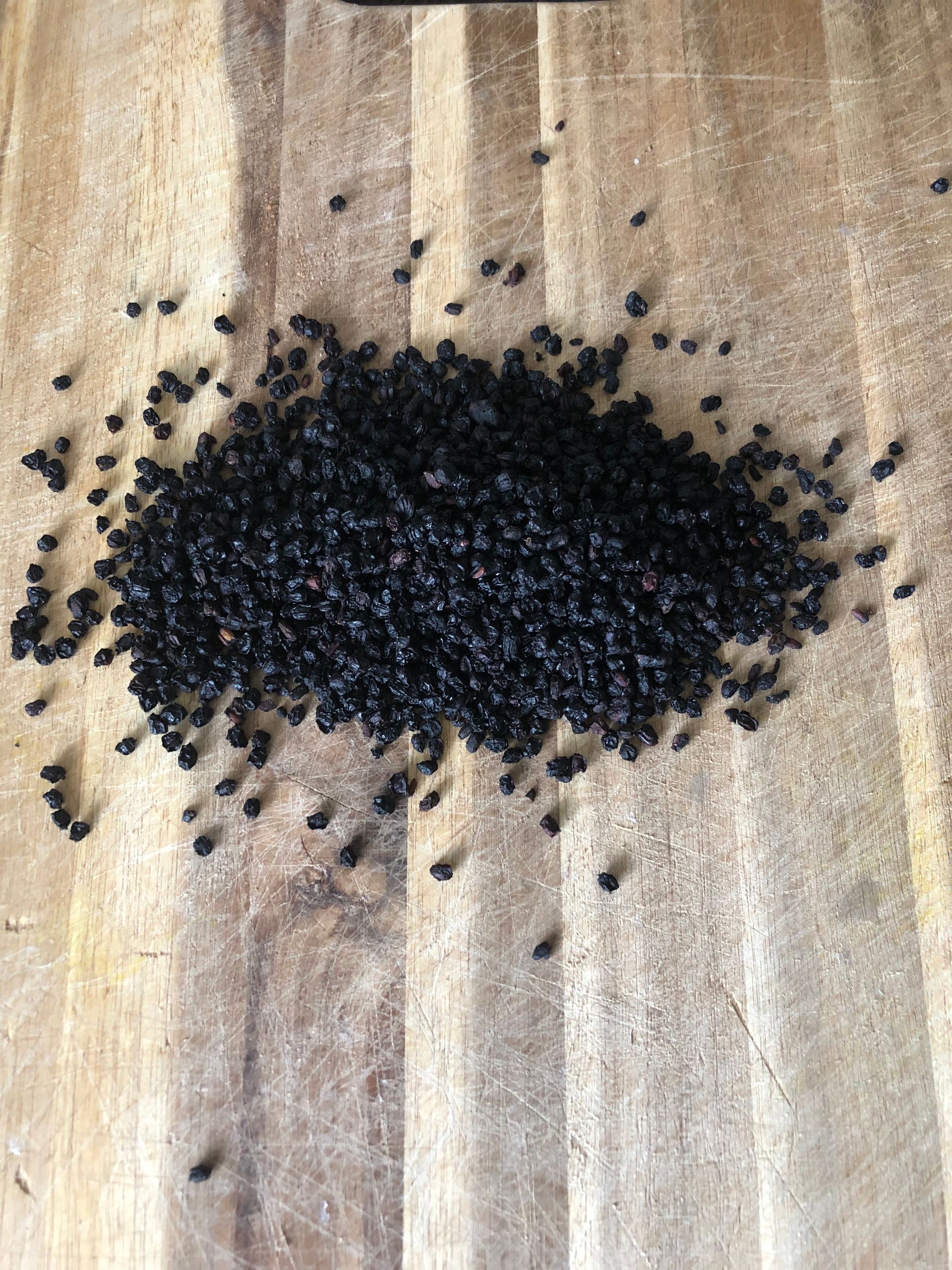 A pile of black seeds on a wooden surface