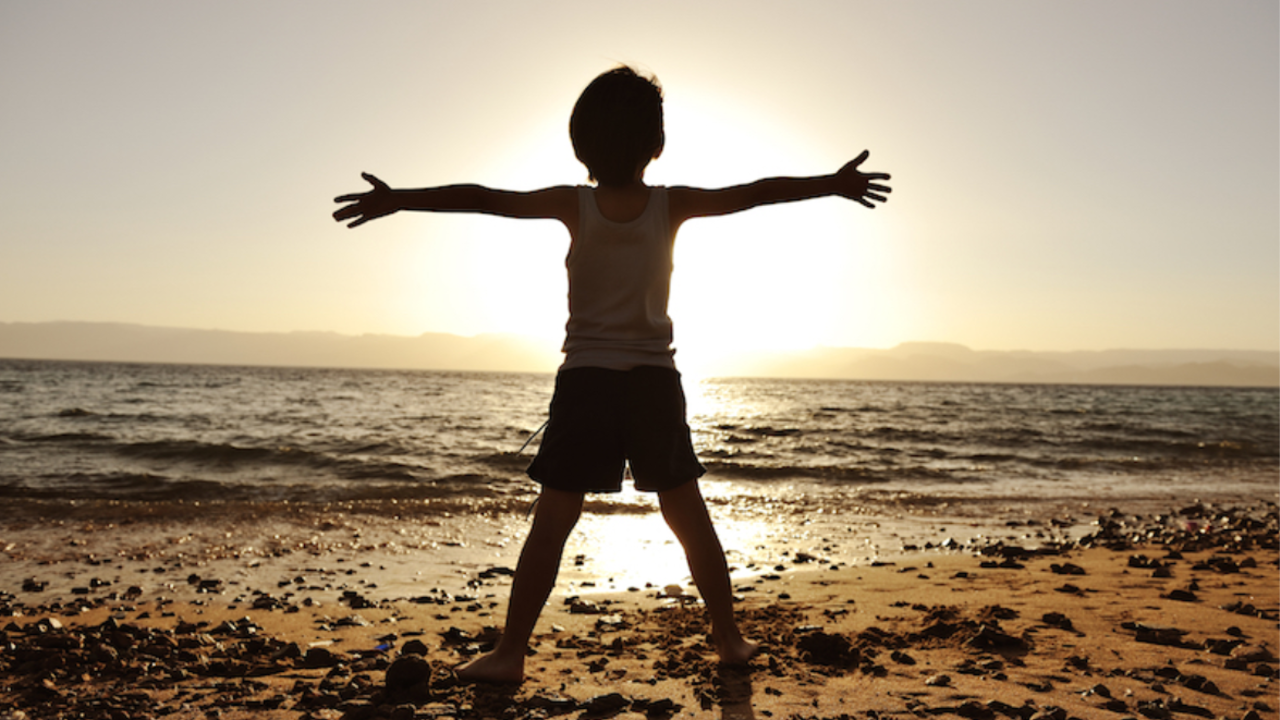 A person standing on a beach with their arms outstretched