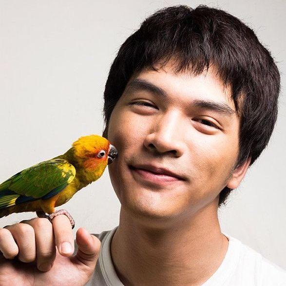 Man smiling with a parrot, symbolizing friendly and approachable customer service from Your Helpful Neighbors.