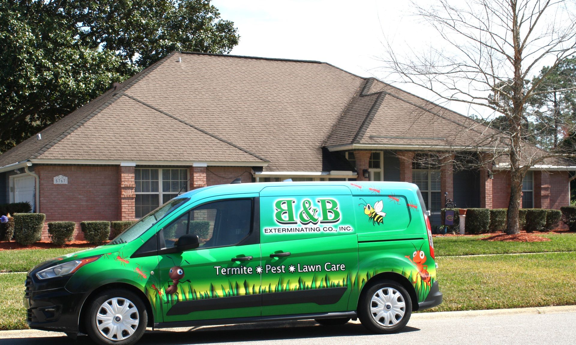 Green and blue H&B Pest Control van parked in front of a brick house.