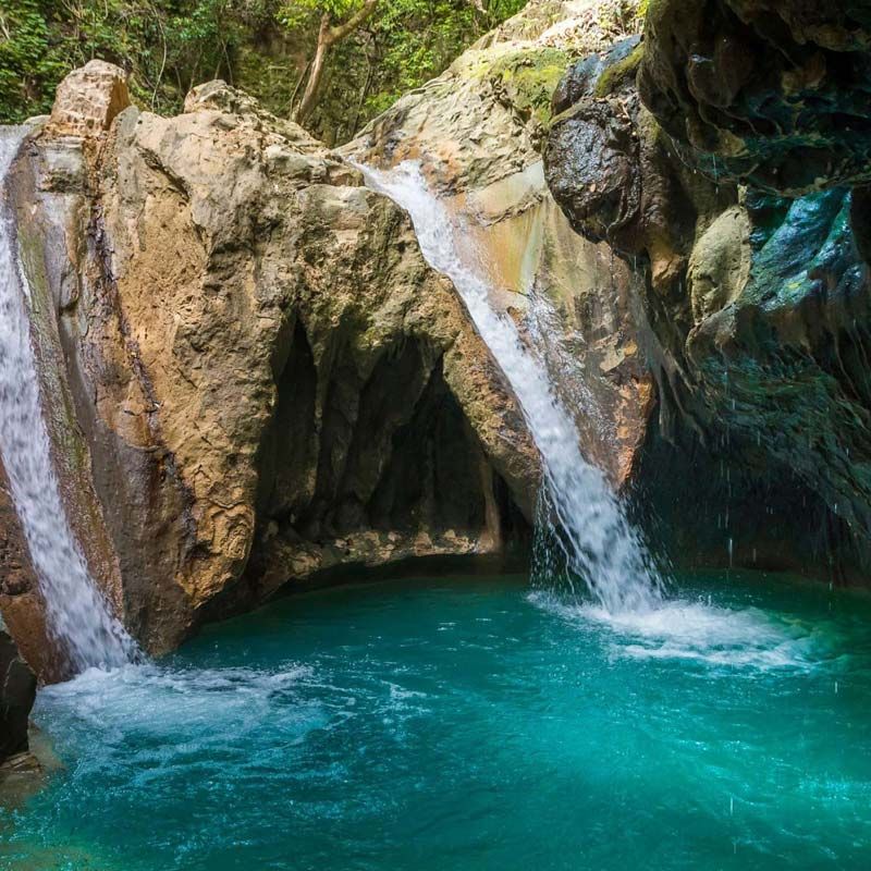 A waterfall is surrounded by rocks and a pool of blue water.